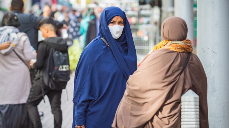 London, UK - 3 November, 2020 - A Muslim woman wearing a chador and a face mask while shopping at Walthamstow market