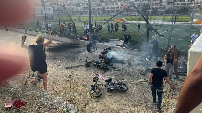 Residents rush to help injured children moments after a rocket attack hit a soccer field in the Druze town of Majdal Shams in the Israeli-controlled Golan Heights, Saturday, July 27, 2024. (AP Photo/Hassan Shams)